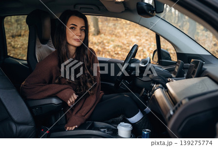Looking at the camera, feeling good. Beautiful woman is sitting in her electric car Looking at the camera, feeling good. Beautiful woman is sitting in her electric car 139275774