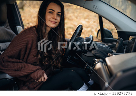 Looking at the camera, feeling good. Beautiful woman is sitting in her electric car Looking at the camera, feeling good. Beautiful woman is sitting in her electric car 139275775