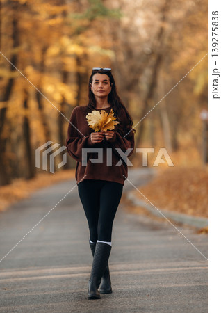 A woman is standing on the asphalt road outdoors at autumn season A woman is standing on the asphalt road outdoors at autumn season 139275838