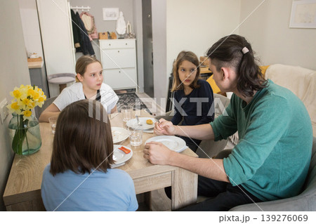 Four people sit together at a table in a dining area, enjoying food and drinks. Four people sit together at a table in a dining area, enjoying food and drinks. 139276069