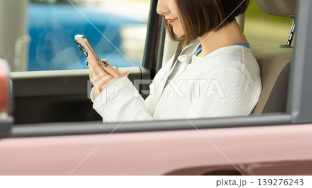 車に乗ってスマートフォンを使う女性 139276243