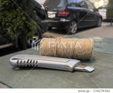A rope and a carpenter's knife for repairs lie on a table in the yard 139276302