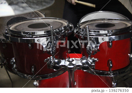A person plays a beat on a red drum kit using wooden drumsticks. 139276350