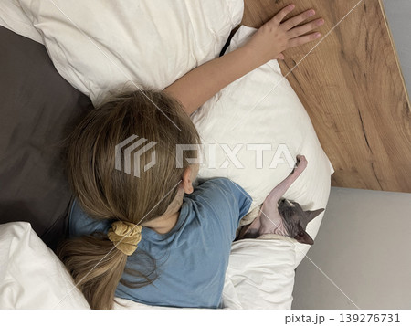 Attractive child and cat pet sleeping together in bedroom. Girl 10 years old and hairless kitten 139276731