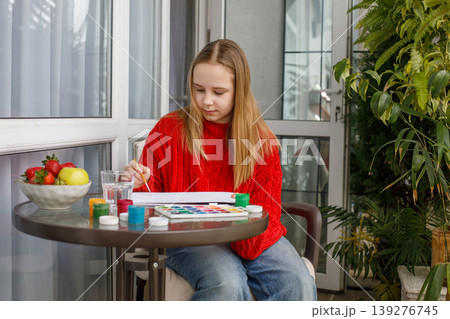 Smiling child drawing pink cats in a sketchbook. Young preteen girl painting Smiling child drawing pink cats in a sketchbook. Young preteen girl painting 139276745
