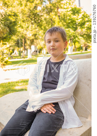 Cute child boy sitting in park outdoors Cute child boy sitting in park outdoors 139276760