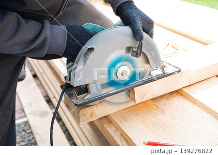 Carpenter man using circular saw to cut wooden plank Carpenter man using circular saw to cut wooden plank 139276822