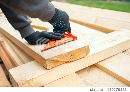 Carpenter measuring and marking wooden planks, frame construction. 139276831