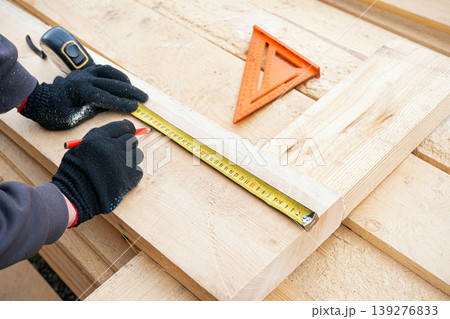 Carpenter measuring and marking wooden planks, frame construction. Carpenter measuring and marking wooden planks, frame construction. 139276833