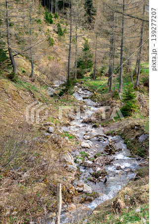A mountain stream flowing between the hills of the mountains after a snow melts 139277207