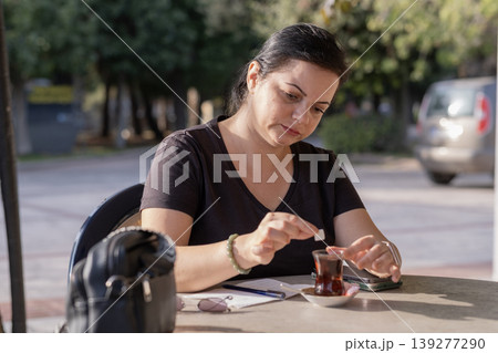 Freelancer Woman Handling Paperwork in Coffee Shop. Freelancer Woman Handling Paperwork in Coffee Shop. 139277290