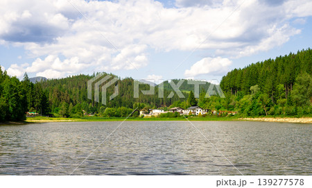 Amazing panoramic mountain landscape with an alpine lake against a cloudy sky Amazing panoramic mountain landscape with an alpine lake against a cloudy sky 139277578