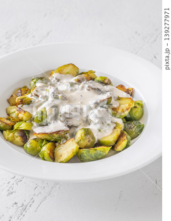 Roasted Brussels sprouts with creamy blue cheese sauce in white bowl 139277971