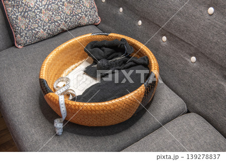 Soft black yarn balls with knitting needles in basket 139278837