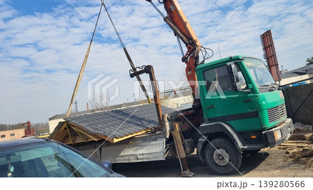 Green manipulator truck lifting building materials on a construction site, heavy machinery logistics, industrial project 139280566