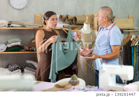 Dissatisfied female client with dress quarrels with tailor Dissatisfied female client with dress quarrels with tailor 139281447