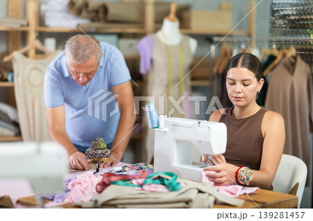 Girl master sew clothes in sewing machine, senior craftsman draw dress pattern 139281457