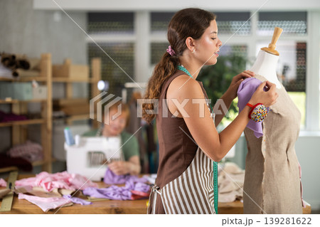 Female fashion designer working with mannequin and sewing fabric Female fashion designer working with mannequin and sewing fabric 139281622