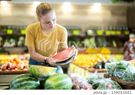 Female shopper selects ripe watermelon at grocery store 139281681
