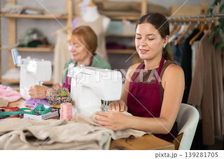 Elderly and young women seamstresses sewing on machine Elderly and young women seamstresses sewing on machine 139281705