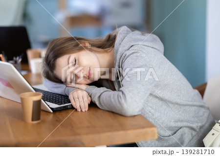 Tired woman sleeping in the office with her head on table Tired woman sleeping in the office with her head on table 139281710