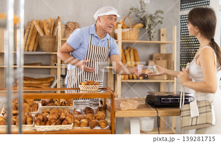 Elderly man seller gives box of pastries to woman buyer 139281715