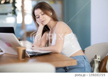 Tired woman sleeping in the office with her head on table Tired woman sleeping in the office with her head on table 139281725