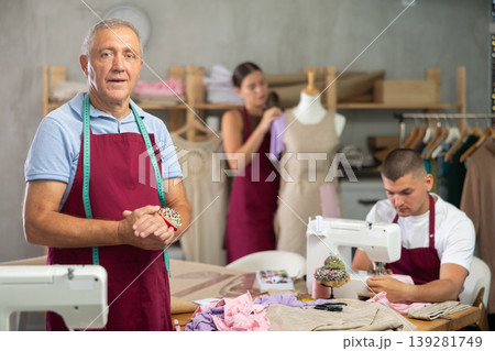 Senior man fashion designer is in office, guy sewing clothes, girl work with mannequin in background 139281749