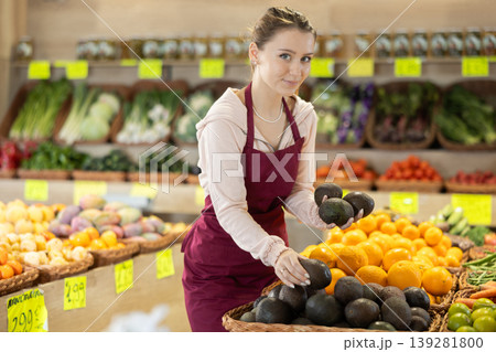 Female grocery store employee places fresh kiwis into crates on sales floor 139281800