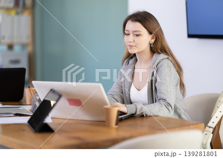 Young woman sitting at desk and working on laptop 139281801