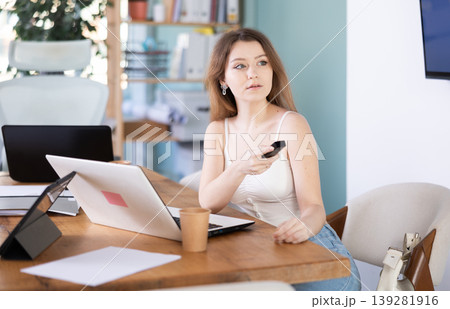 Young woman with wireless remote watching presentation in office Young woman with wireless remote watching presentation in office 139281916