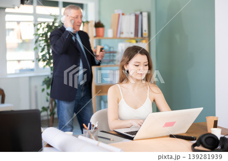 Young woman is typing on a laptop in front of her boss Young woman is typing on a laptop in front of her boss 139281939