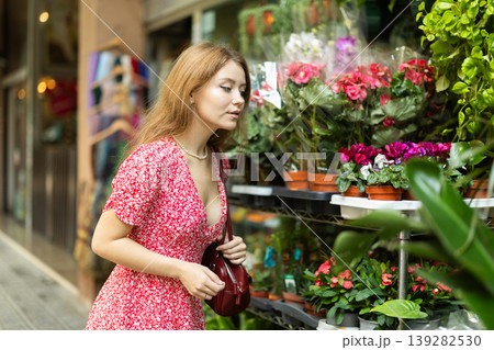 Young woman standing near a display case with plants on the street Young woman standing near a display case with plants on the street 139282530