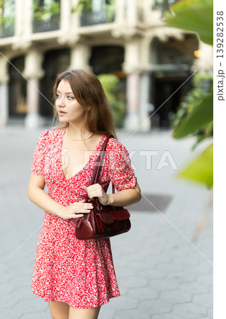 Woman in dress looking around city street on summer day Woman in dress looking around city street on summer day 139282538