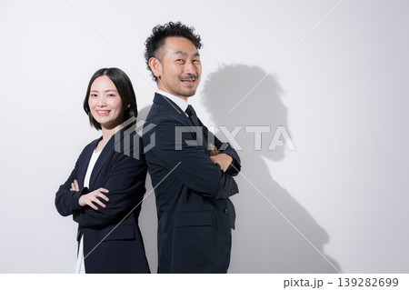 背中合わせで立つ男女ビジネスパーソンの信頼とチームワークイメージ カメラ目線で笑顔 背中合わせで立つ男女ビジネスパーソンの信頼とチームワークイメージ カメラ目線で笑顔 139282699