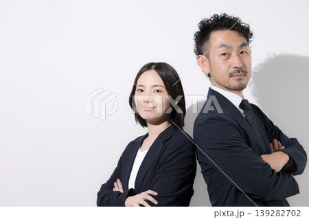 背中合わせで立つ男女ビジネスパーソンの信頼とチームワークイメージ カメラ目線で真剣な表情 背中合わせで立つ男女ビジネスパーソンの信頼とチームワークイメージ カメラ目線で真剣な表情 139282702