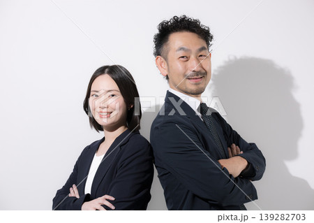 背中合わせで立つ男女ビジネスパーソンの信頼とチームワークイメージ カメラ目線で真剣な表情 背中合わせで立つ男女ビジネスパーソンの信頼とチームワークイメージ カメラ目線で真剣な表情 139282703