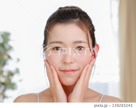 スキンケアで頬に手を当てるナチュラルな日本人女性（美肌・美容） 139283243