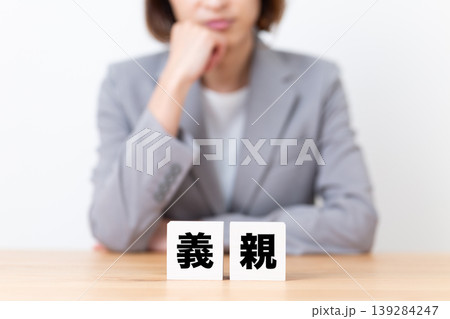 義親のブロックと悩むスーツ姿のミドル女性 義親のブロックと悩むスーツ姿のミドル女性 139284247