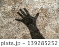 Shadow projection of a human palm on a neutral industrial cement background 139285252