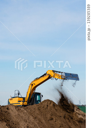 Excavator digging sand on construction site vertical shot 139285389