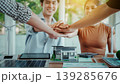 Business team stacking hands over model house and solar panel on desk, sustainable real estate, renewable energy planning, and partnership in modern office. 139285676