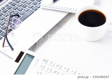 淹れたてのコーヒーを飲みながら、ノートパソコンと電卓でデスクワークをしているイメージ 139286097