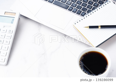 淹れたてのコーヒーを飲みながら、ノートパソコンと電卓でデスクワークをしているイメージ 淹れたてのコーヒーを飲みながら、ノートパソコンと電卓でデスクワークをしているイメージ 139286099