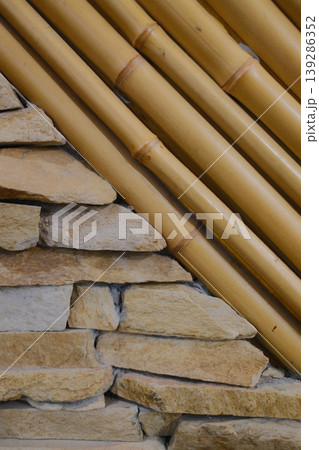 Stacked stones meet parallel bamboo poles at a sharp angle indoors 139286352