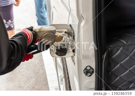 Close up of hand holding fuel nozzle filling car tank at station gasoline energy transportation routine service and vehicle maintenance daily use Close up of hand holding fuel nozzle filling car tank at station gasoline energy transportation routine service and vehicle maintenance daily use 139286359
