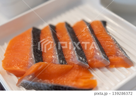 Close up of fresh salmon sashimi slices with skin on white plate rich color and texture premium seafood ready for sushi meal healthy protein and omega nutrition Close up of fresh salmon sashimi slices with skin on white plate rich color and texture premium seafood ready for sushi meal healthy protein and omega nutrition 139286372