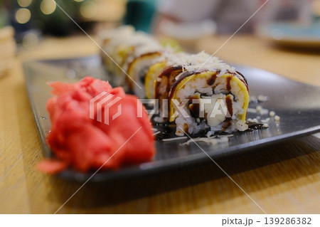 Several sushi rolls are presented next to pickled ginger on a dark plate 139286382