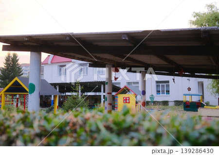Outdoor playground for children with colorful playhouses and bushes in the foreground Outdoor playground for children with colorful playhouses and bushes in the foreground 139286430