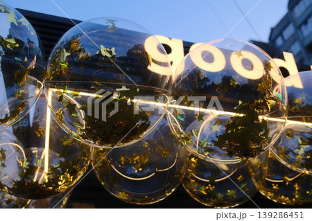 Transparent balloons with stars float, and the word Good is lit up on a building 139286451